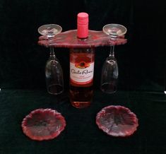 three wine glasses and two empty wine bottles on a table with red glassware in front of it