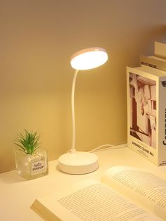 an open book sitting on top of a table next to a lamp and some books