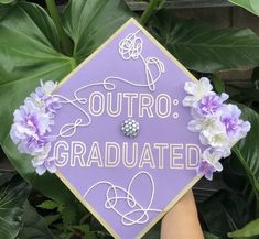 someone holding up a purple graduation cap that says,'outro graduated'with flowers on it