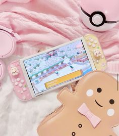 a cell phone sitting on top of a white blanket next to a pink purse and other items