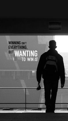 a man is walking in front of a large screen with the words winning isn't everything, but wanting to win is