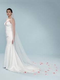 a woman in a white wedding dress with rose petals on the floor and veil over her head