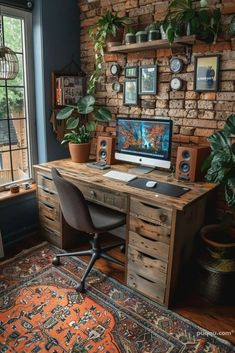 a desk with a computer on top of it in front of a window filled with potted plants