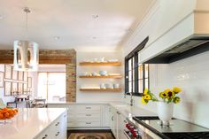 a large kitchen with white cabinets and black counter tops, sunflowers on the island