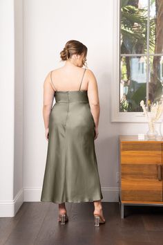 a woman standing in front of a window wearing a green dress