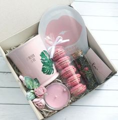 pink macaroons in a box with candles and other items