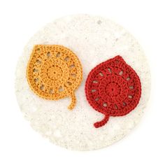 two crocheted hats sitting on top of a white plate next to each other