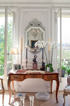 a room with a table, mirror and vases on the floor in front of it