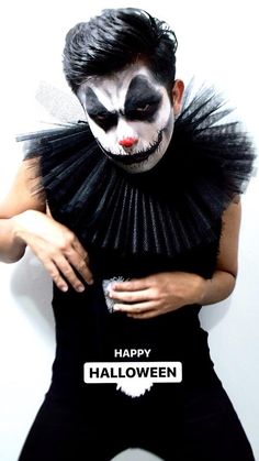 a man dressed in black and white is posing for the camera with his hands on his chest