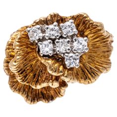 14k yellow gold ring. This beautiful and unusual ring is a chased cockscomb form, decorated with a cluster of round brilliant cut diamonds, approximately 0.23 TCW, prong set. The ring is finished by split shoulders and a double shank, patterned in a branch motif. Marks: 14k Dimensions: 11/16" across the top x 1/2" wide Weight: 5.3 gross dwt Size: 5 *please note: this ring cannot be sized without making a break in the pattern of the shank