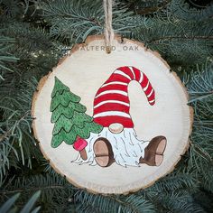 a wooden ornament with an image of a gnome and a christmas tree on it