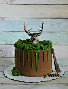 a cake with green icing and a deer's head sticking out of it