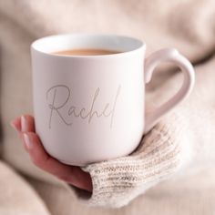 a person holding a coffee mug with the word rachel written on it