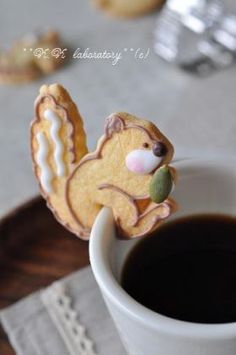 a cookie shaped like a squirrel on top of a cup of coffee