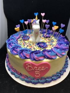 a birthday cake decorated with an unicorn and hearts