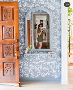 a woman taking a selfie in the mirror of a blue and white wallpapered room