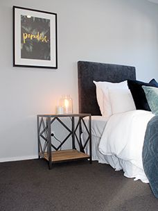 a bedroom with a bed, night stand and two candles on the end tables in front of it