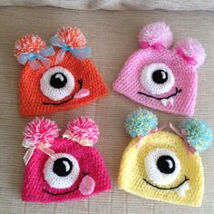 four crocheted hats with eyes and pom poms