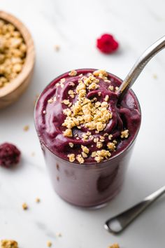 a close up of a dessert in a glass on a table with raspberries