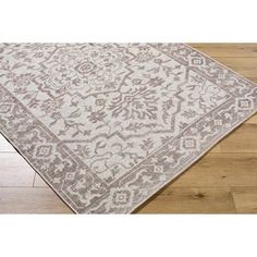 an area rug on the floor with wood floors and white walls in the background,