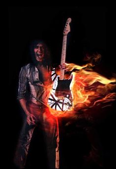 a man holding a guitar in his right hand with fire behind him and the background is black