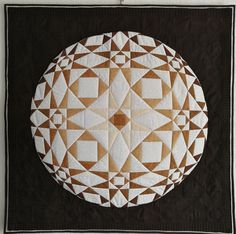 a black and white quilt with a circular design on it's center, in brown and white