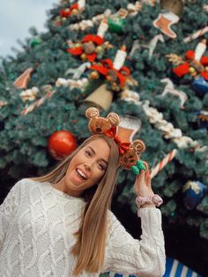 a woman is standing in front of a christmas tree holding her hair up to her face