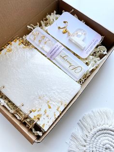 an open box that has some items inside of it on a white tablecloth and tassels