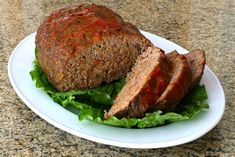 meatloaf with lettuce and tomato sauce on a white plate sitting on a granite counter top