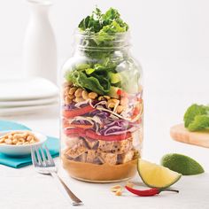 a mason jar filled with salad ingredients and garnished with lettuce, red onion, chickpeas