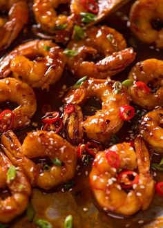 closeup of cooked shrimp with sauce and garnishes on a serving platter