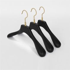 three black plastic hangers with gold hooks