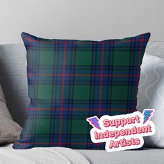 a green plaid pillow with the words support independent artists in red and blue on it