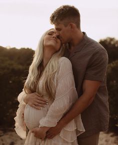 a man and woman kissing each other on the beach