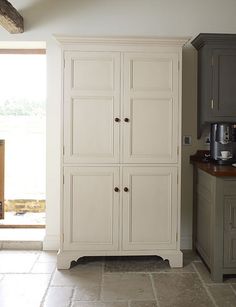 a large white cabinet sitting in the middle of a kitchen next to a counter top