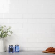 a white vase filled with flowers sitting on top of a counter next to two croissants