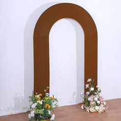 two vases filled with flowers sitting on top of a wooden floor next to an arch