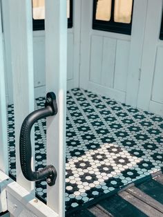 a door handle on the side of a white and black tiled porch with blue tiles