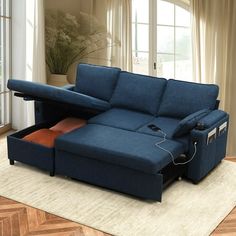 a living room with a blue couch and a pull out bed on the floor in front of a large window