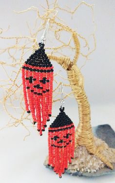 a pair of red and black beaded earrings hanging from a tree branch