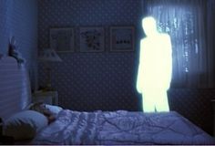 a person standing in the dark next to a bed