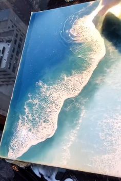 an aerial view of the ocean with waves coming in from the shore and buildings on the other side