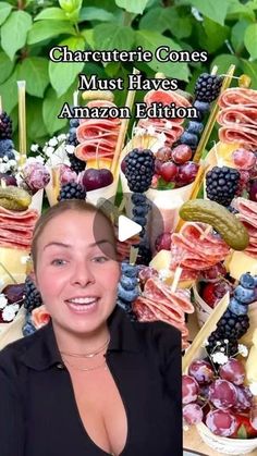 a woman is smiling in front of an array of fruit and cheeses