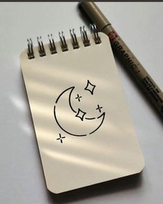 a notepad with a drawing of a crescent moon and stars on it next to a marker pen