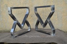 two metal sculptures sitting next to each other on a stone slab in front of a wall