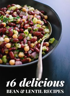 a bowl filled with beans and vegetables on top of a table next to a spoon