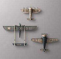 three metal airplanes mounted to the side of a wall