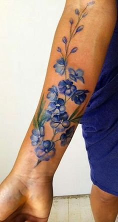 a woman's arm with blue flowers on the left side of her body and one flower in the middle