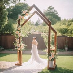 a woman in a wedding dress standing under a wooden arch with flowers on the side