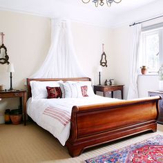 a bedroom with a bed, dressers and rug in front of a large window